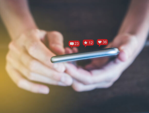 holding mobile phone with notification symbols - girl uses smart Por qué la desregulación de las redes sociales impulsada por Trump es mala para la libertad de expresión