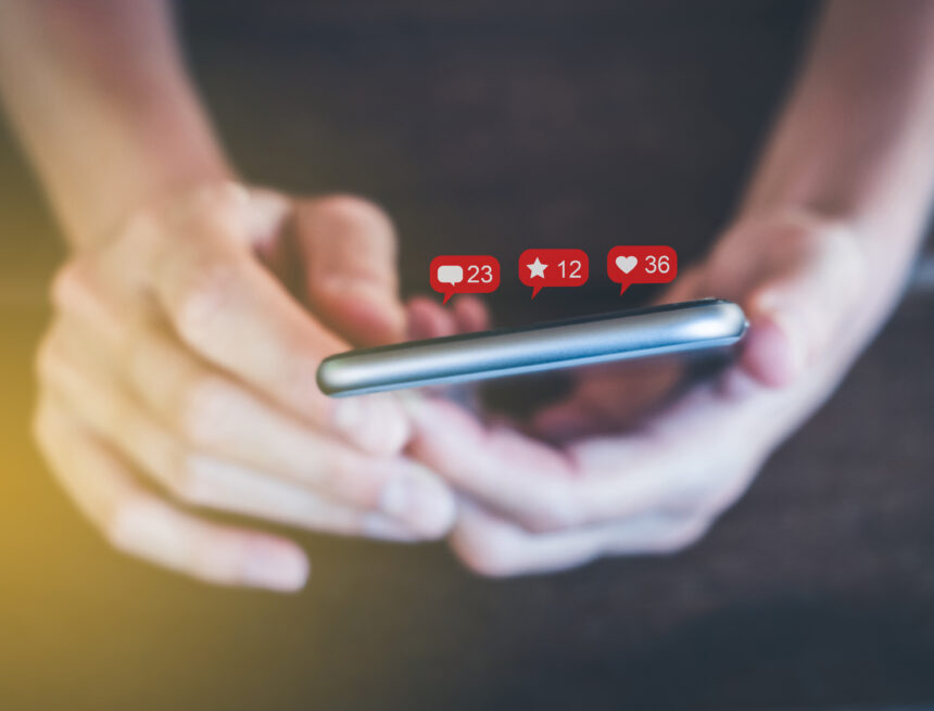 holding mobile phone with notification symbols - girl uses smart Por qué la desregulación de las redes sociales impulsada por Trump es mala para la libertad de expresión